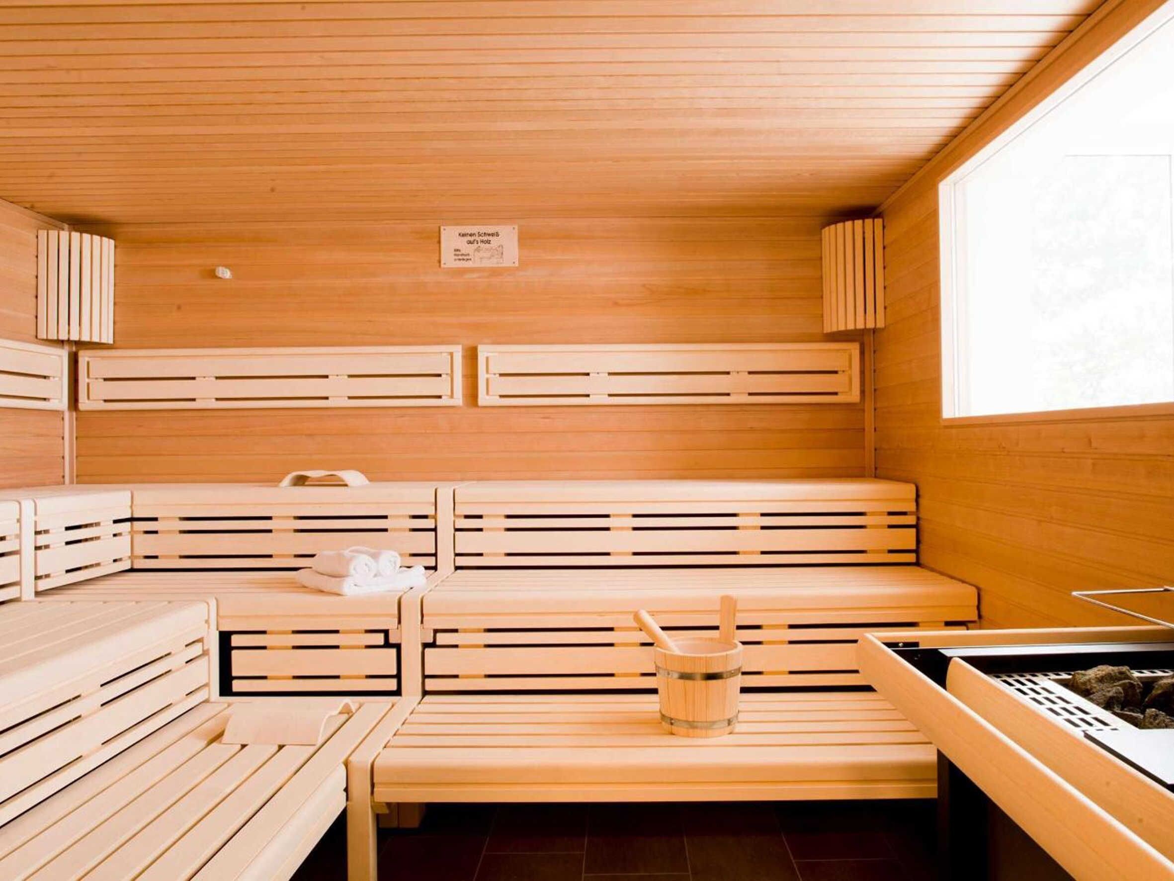 A sauna with wooden benches, a wooden bucket, and a sign on the wall.