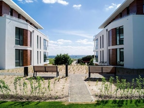 A modern building with a central pathway, benches, and a view of the sea. - Apartment Sonnentraum Südkap-Pelzerhaken - App. Sonnentraum, 62m², terrace, up to 3 (Neustadt in Holstein)