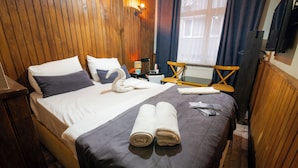 Et hotelværelse med seng, stol, bord og et vindue med gardiner.