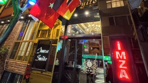 En hotelindgang med flag, et neon-skilt og en trappe ind.