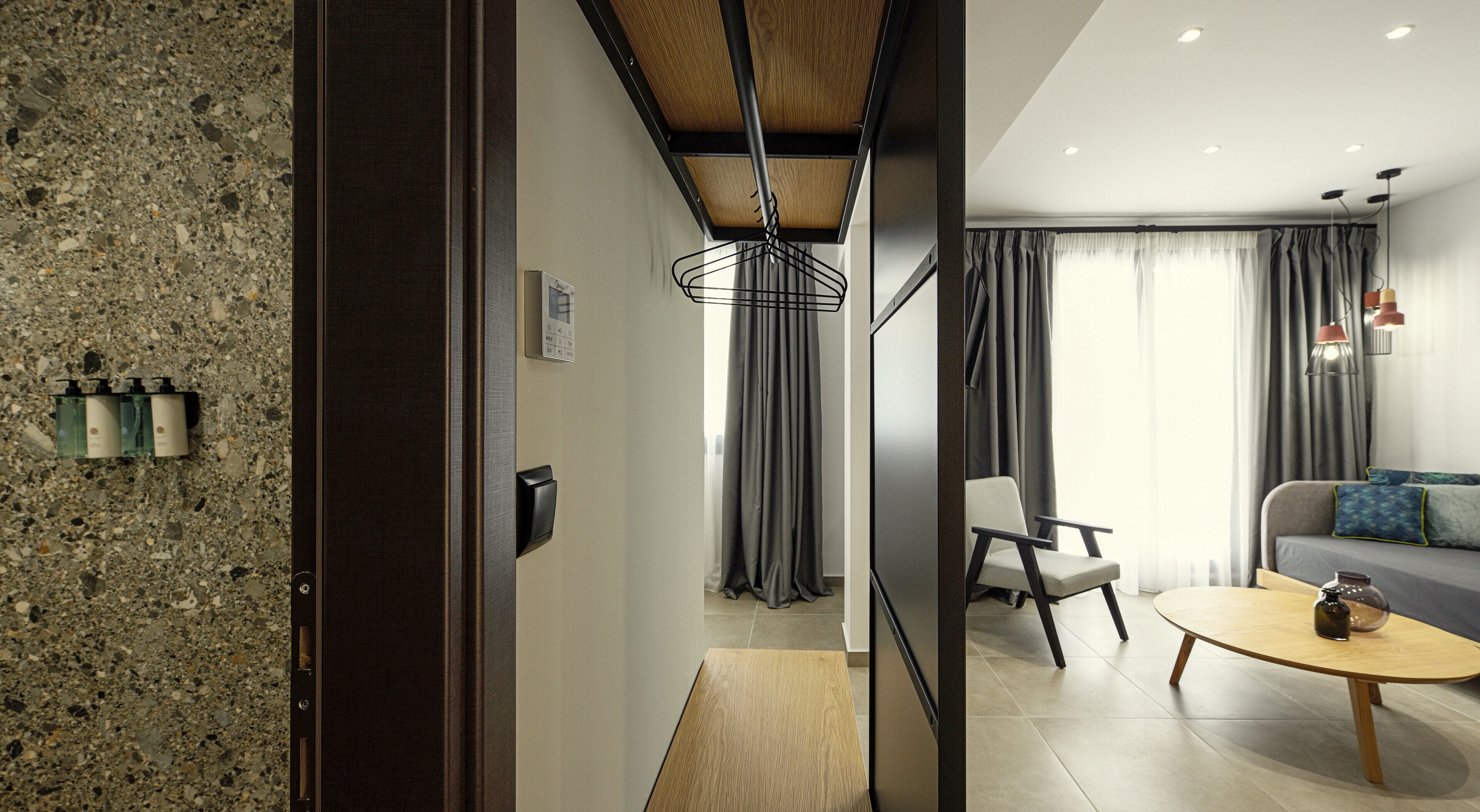Een moderne hotelkamer met een granieten aanrecht, een houten eettafel, een bank en een stoel.