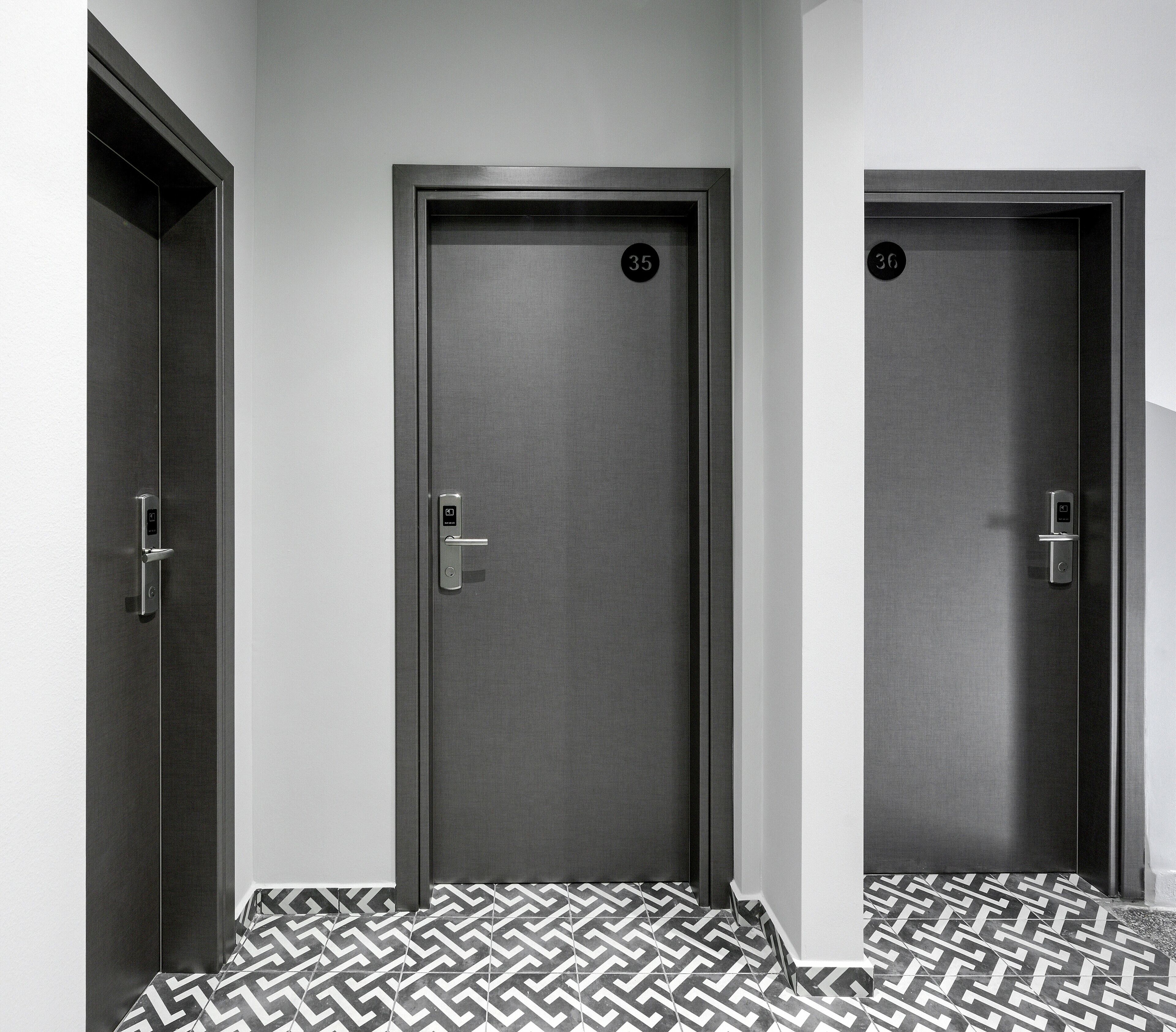 Three doors with numbers 35 and 36, a hallway with patterned flooring, and a modern door handle design.