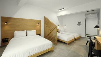A hotel room with a large bed, two smaller beds, a desk, and a chair.