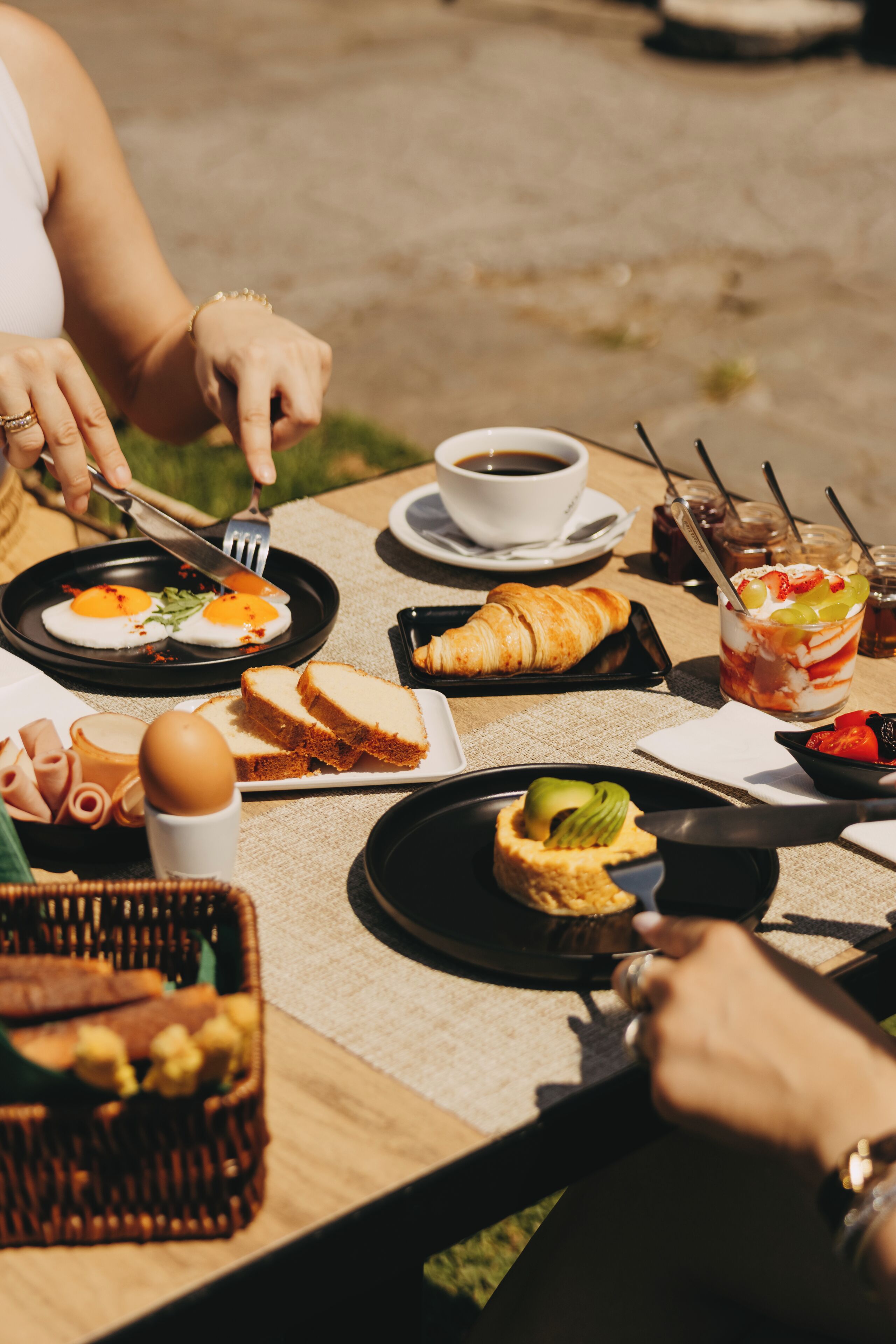 A dining table with breakfast items, including eggs, bread, and a croissant.
