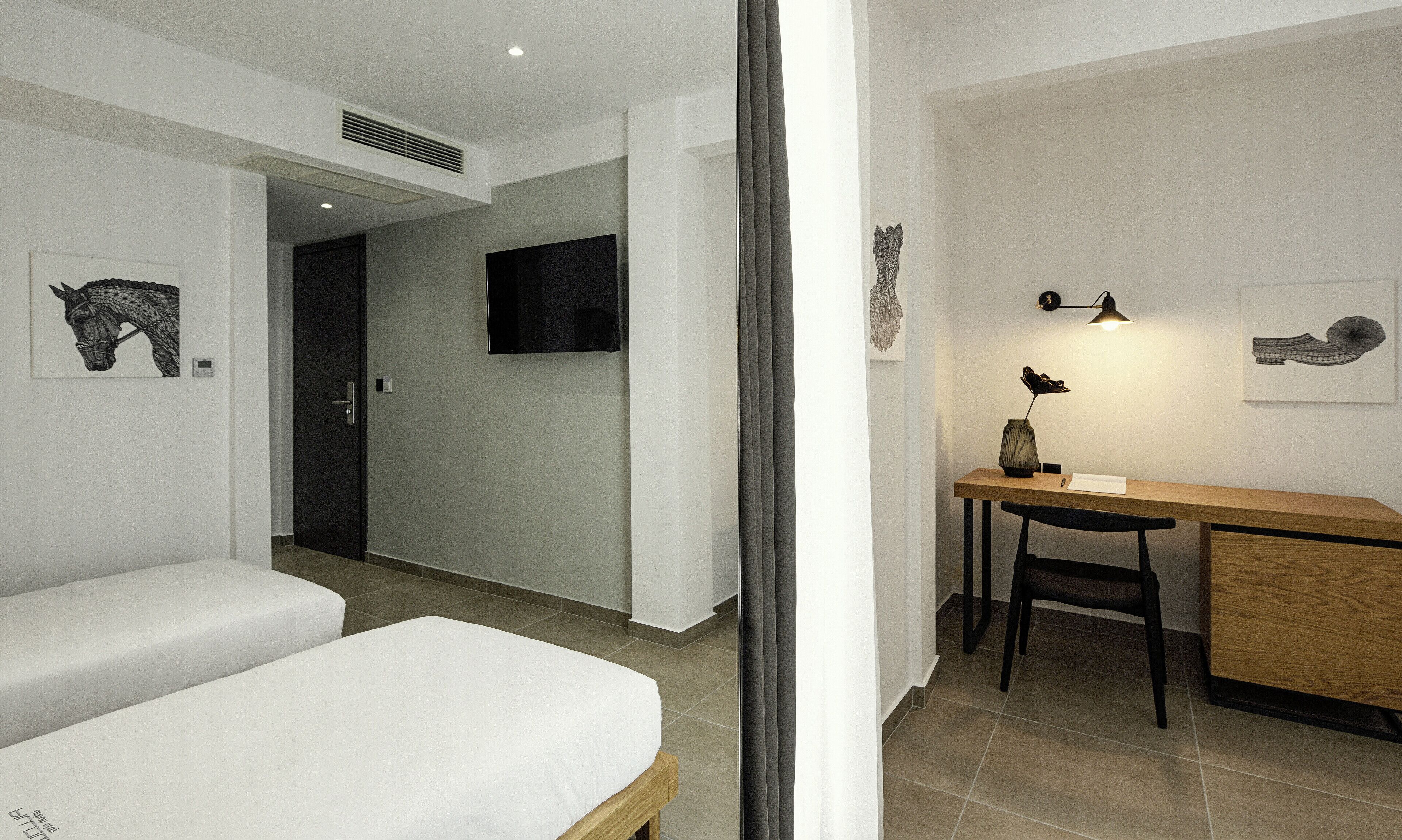 Habitació d'hotel moderna amb llit, escriptori i televisió.