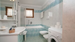 A bathroom with a sink, toilet, bathtub, and washing machine. - Apartment in the heart of Valle di Sole (Mezzana-Marilleva)