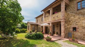 A stone building with a courtyard, outdoor seating, and potted plants. - Podere San Gregorio (Pienza)