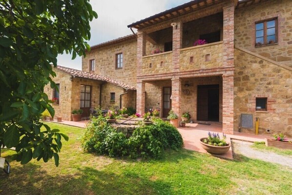 Un edificio de piedra con patio interior, que cuenta con un jardín central con macetas y un espacio de descanso.