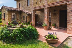 A stone building with a tiled roof, a covered patio area, and potted plants. - Podere San Gregorio (Pienza)