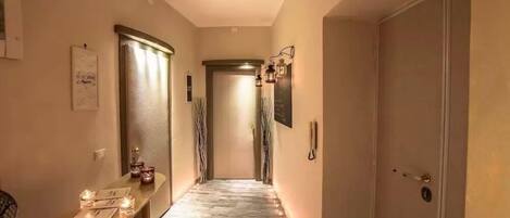 Un pasillo con piso de madera, una recepción con espejo y una puerta al final.