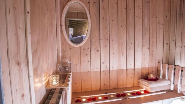 A wooden cabin interior with a bench, a mirror, and candles. - Boutique Roma D'Autore (Rome)