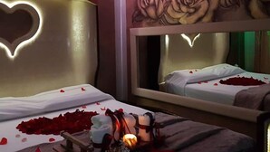 A hotel room with a bed adorned with rose petals and a heart-shaped light fixture on the headboard. - Boutique Roma D'Autore (Rome)
