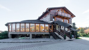 Un edificio de dos pisos con un balcón, ventanas amplias y una escalera que conduce al nivel superior.