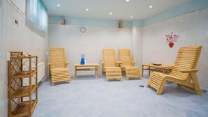 Un cuarto de spa con sillas de madera, una mesita y un estante con artículos de aseo.