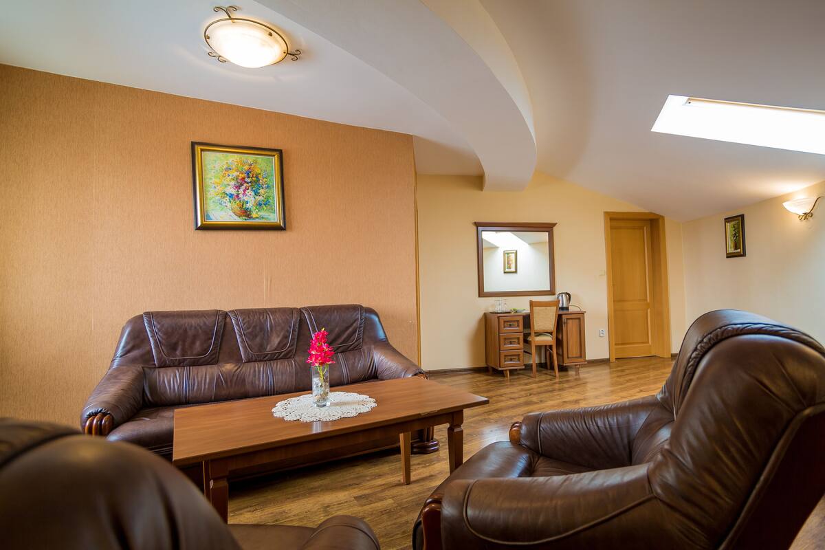 Uma sala de estar com um sofá de couro marrom, uma mesa de centro de madeira e um armário de madeira.