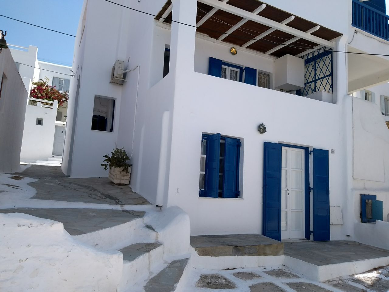 A white building with blue shutters and a small balcony.