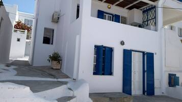 A white building with blue shutters and a small balcony.
