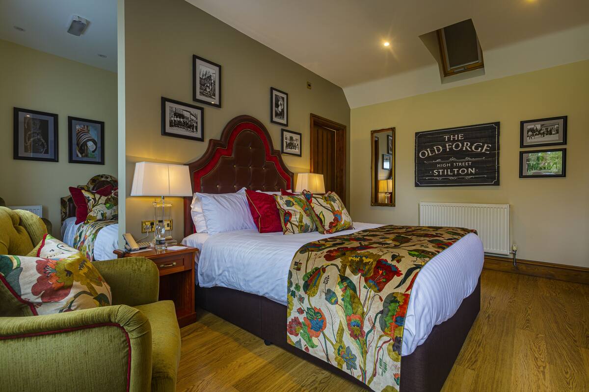 Habitación de hotel con una cama grande, una mesita de noche, una silla y una pared decorada con cuadros y un letrero.