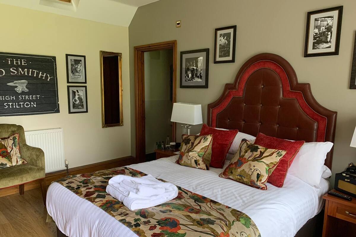 Una cama bien hecha con ropa de cama floral, cabecera roja y un cartel en la pared.
