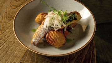 Un plato de comida con pescado y verduras sobre una mesa de madera.