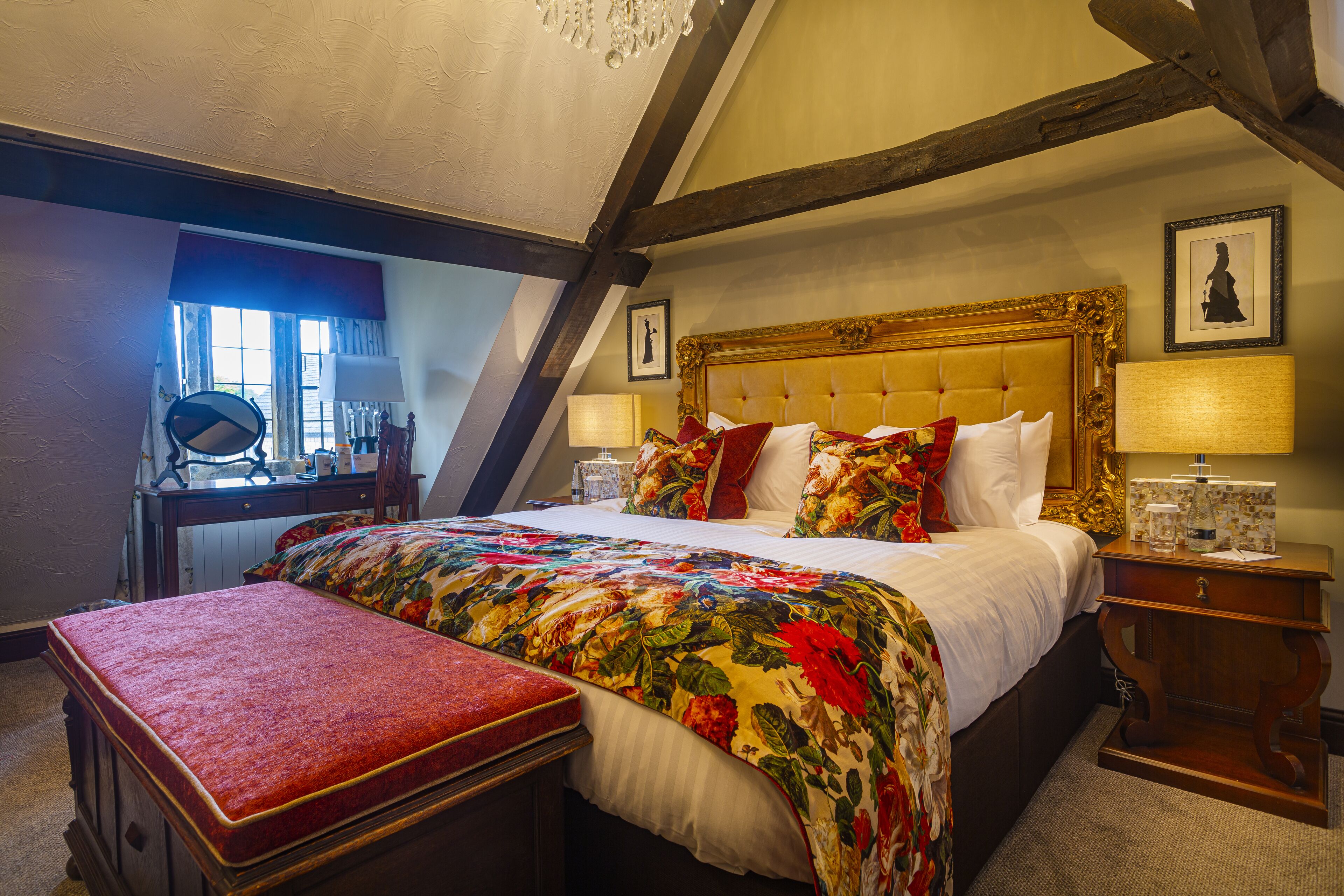A bedroom with a large bed, a wooden bench, a desk, and a chair.