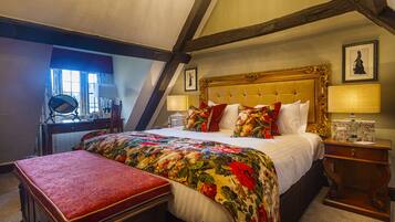 A bedroom with a large bed, a wooden bench, a desk, and a chair.