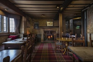 A cozy pub with wooden furniture, a fireplace, and stone walls. - The Bell Inn Hotel, Stilton, Cambridgeshire (Peterborough)