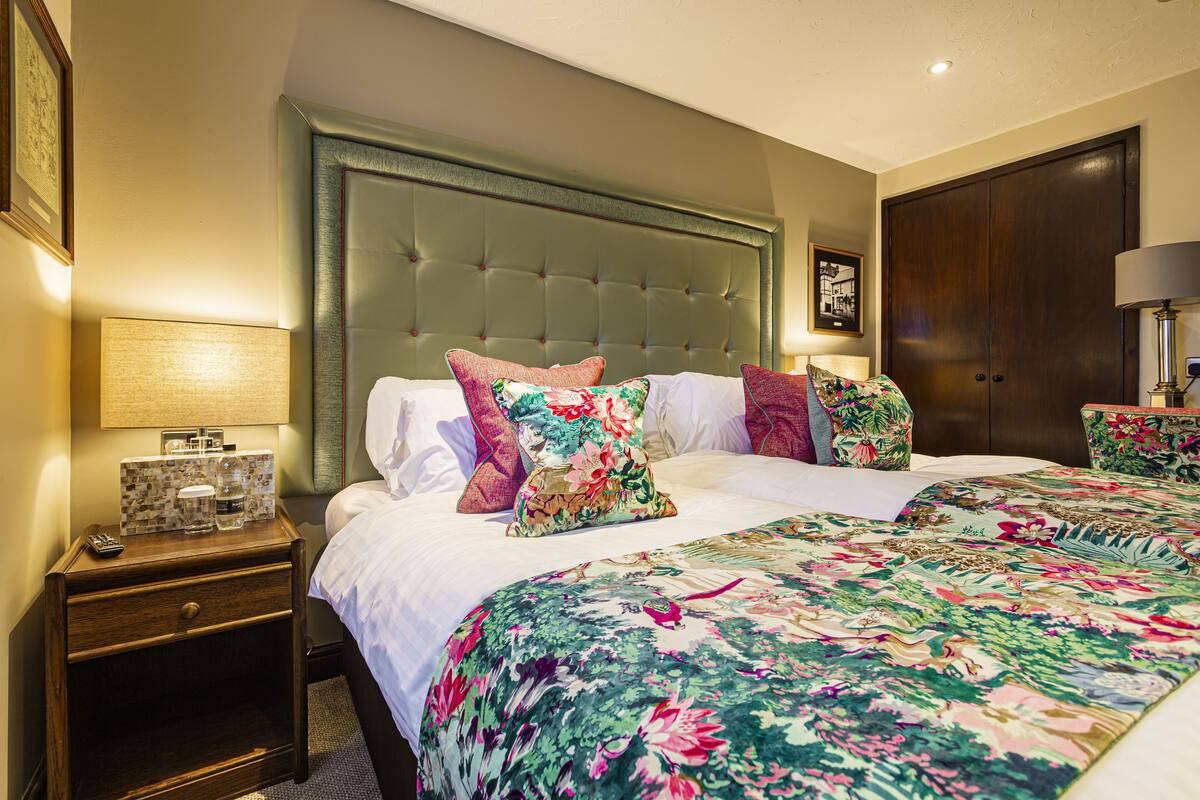 Una habitación de hotel con una cama grande, una mesita de noche con lámpara y un armario.