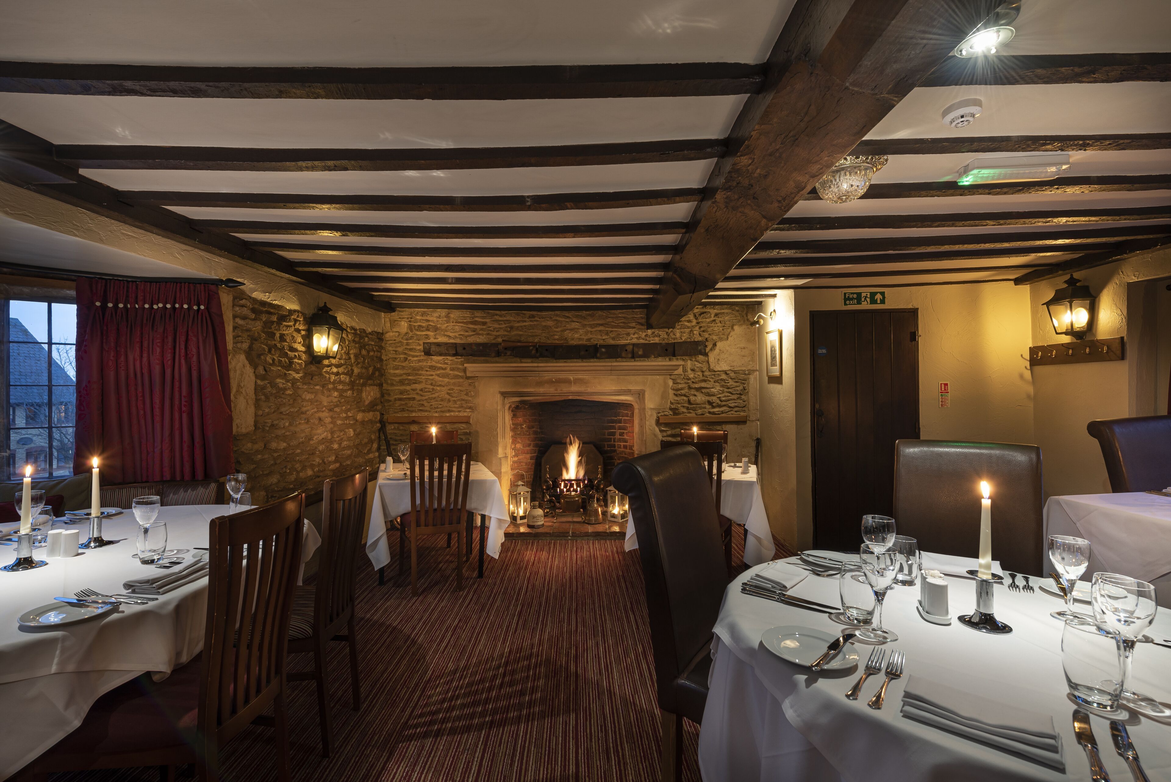 A restaurant with wooden beams, stone walls, and tables set for dining.
