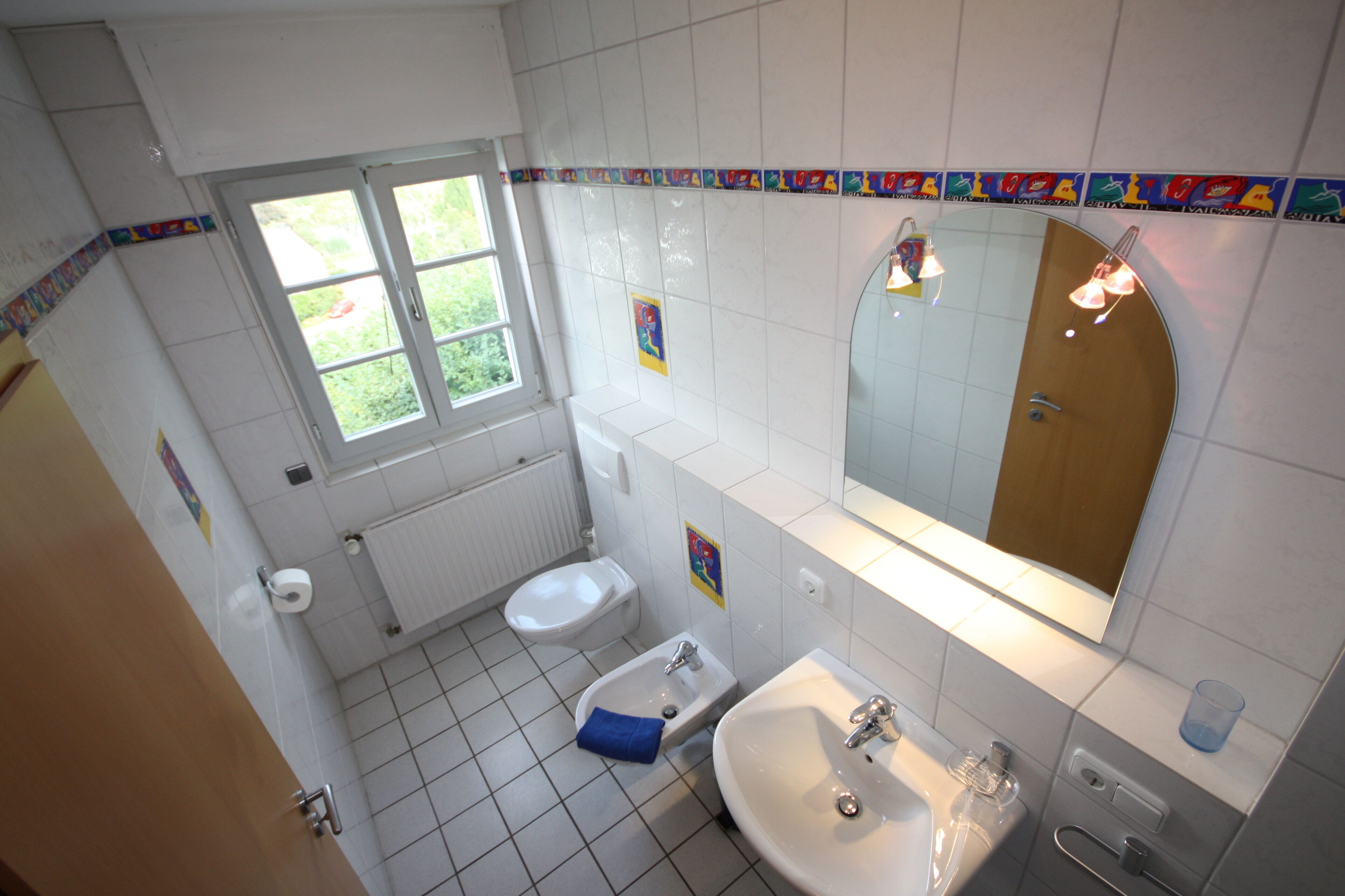 Une salle de bain équipée de toilettes, d’un bidet, d’un lavabo et d’un miroir.
