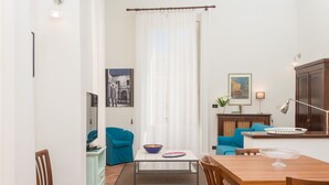 Una sala de estar con una mesa de comedor, sillas, un sofá, una mesa de centro y un televisor.