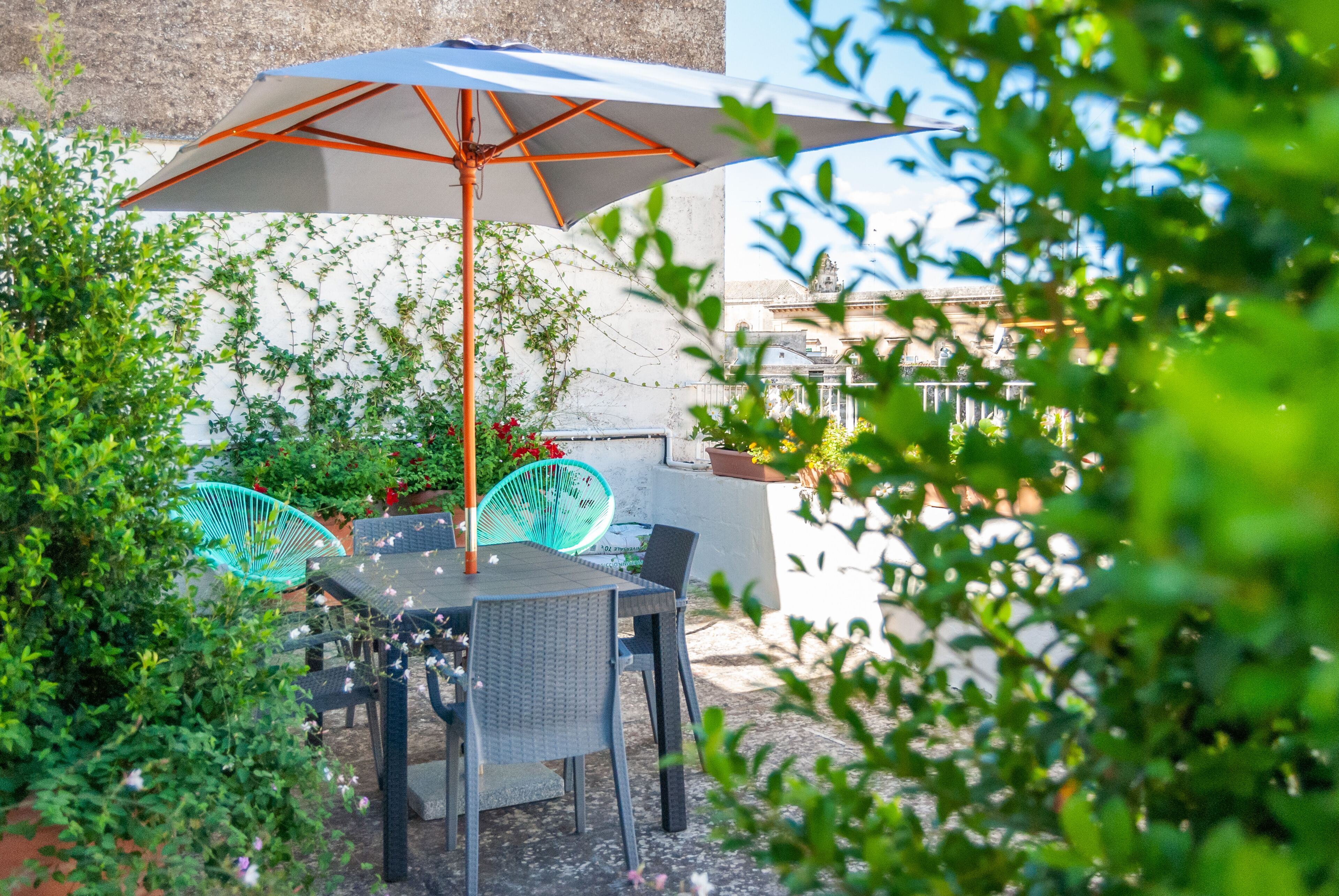 An outdoor patio with a table and chairs, an umbrella, and potted plants.
