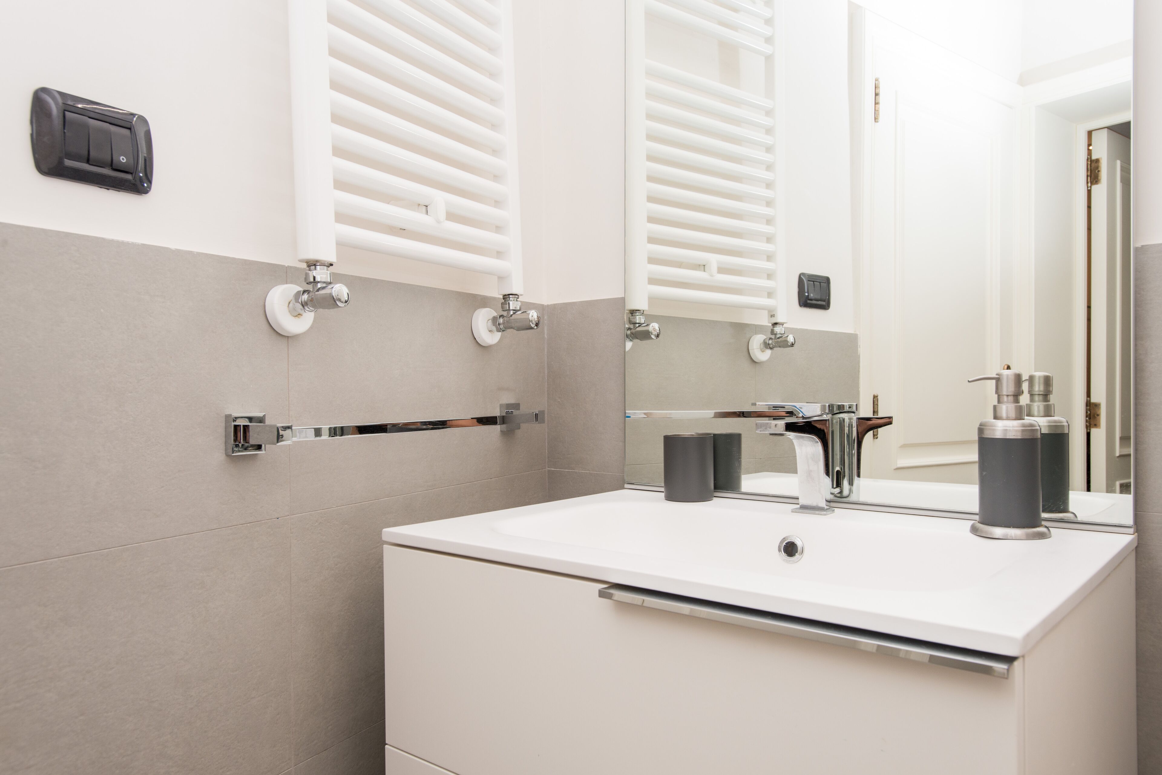 A modern bathroom with a white sink, a mirror, and a towel rack.