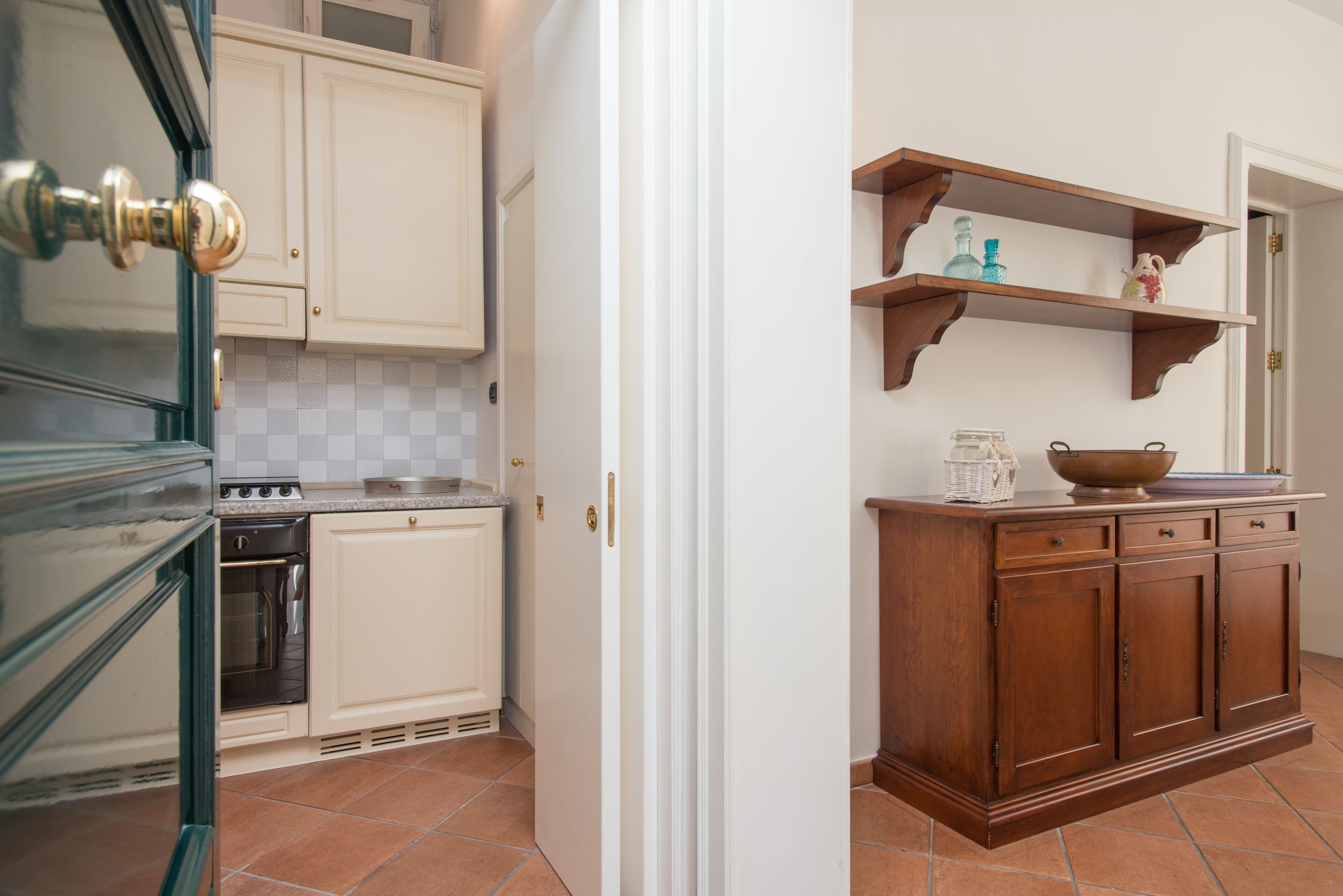 A kitchen with white cabinets, a wooden countertop, and a tiled backsplash.