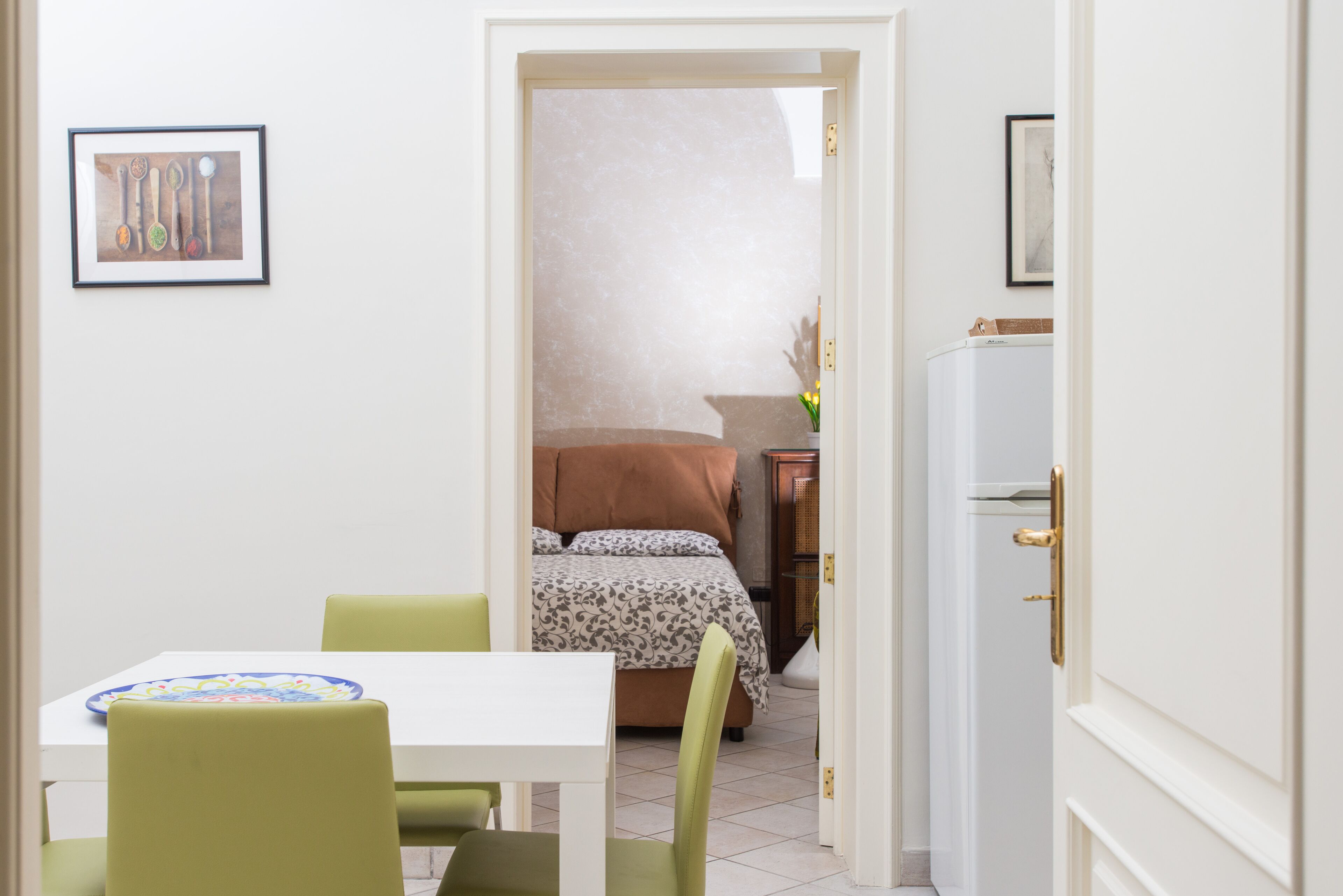 A room with a bed, a table with chairs, and a door leading to another room.