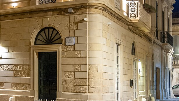 Un edificio histórico con fachada clásica, ventanas amplias y una entrada destacada.