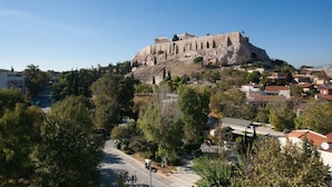 A view of an ancient ruin on a hill with modern buildings in the foreground. - New Acropolis Museum Flat (Athens)