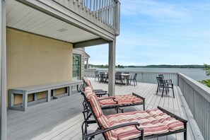 Une terrasse avec des chaises longues et une table, donnant sur une étendue d’eau.