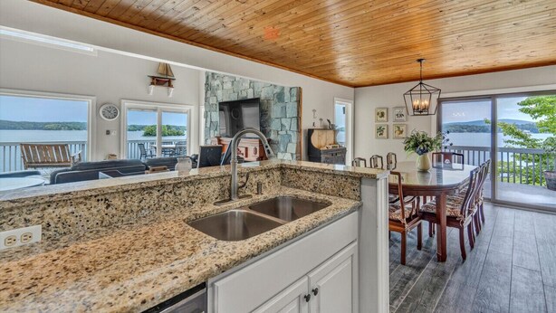 A kitchen with granite countertops, a stone backsplash, and a large window overlooking a scenic view.