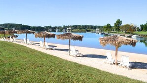 A beach with thatched umbrellas and white lounge chairs along the water's edge.