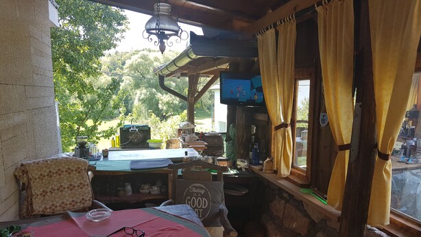 A rustic room with a wooden table, a bench, and a window with curtains. - Apartments Una Riverlodge (Bihac)