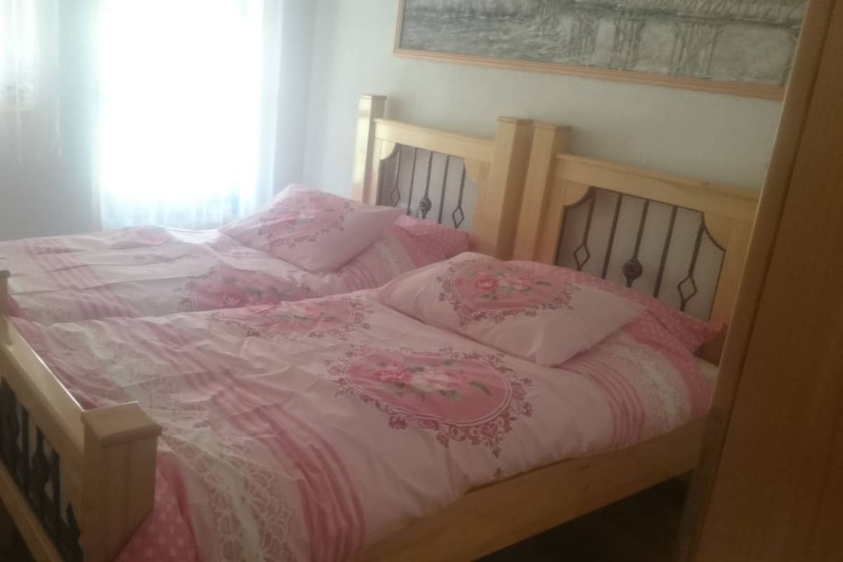 Een bed met houten frame en bloemenprint beddengoed.