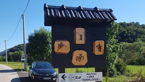 A wooden sign with hiking symbols and a directional arrow indicating a 20m distance to a hostel named "UNA RIVERLODE". - Apartments Una Riverlodge (Bihac)