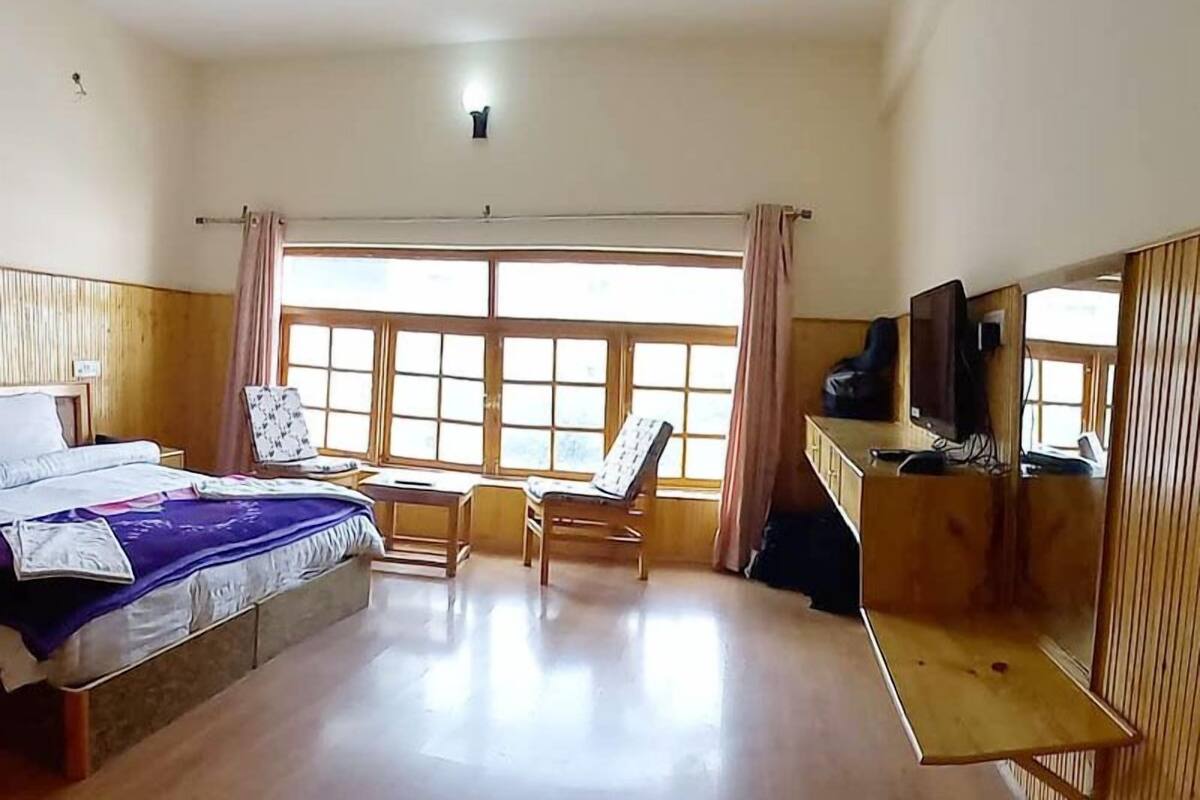A hotel room with a bed, a desk, a chair, and a television.