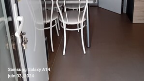 Uma cozinha compacta com área de refeições, com geladeira, micro-ondas, cafeteira e painel de azulejos.