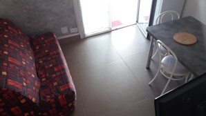 Uma sala de estar moderna com um sofá estampado, uma mesa de jantar com um apoio para copo e uma cadeira.