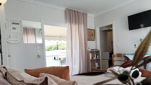 A hotel room with a bed, a television, a bookshelf, and a window with curtains. - Acropolis View Charming Loft (Athens)