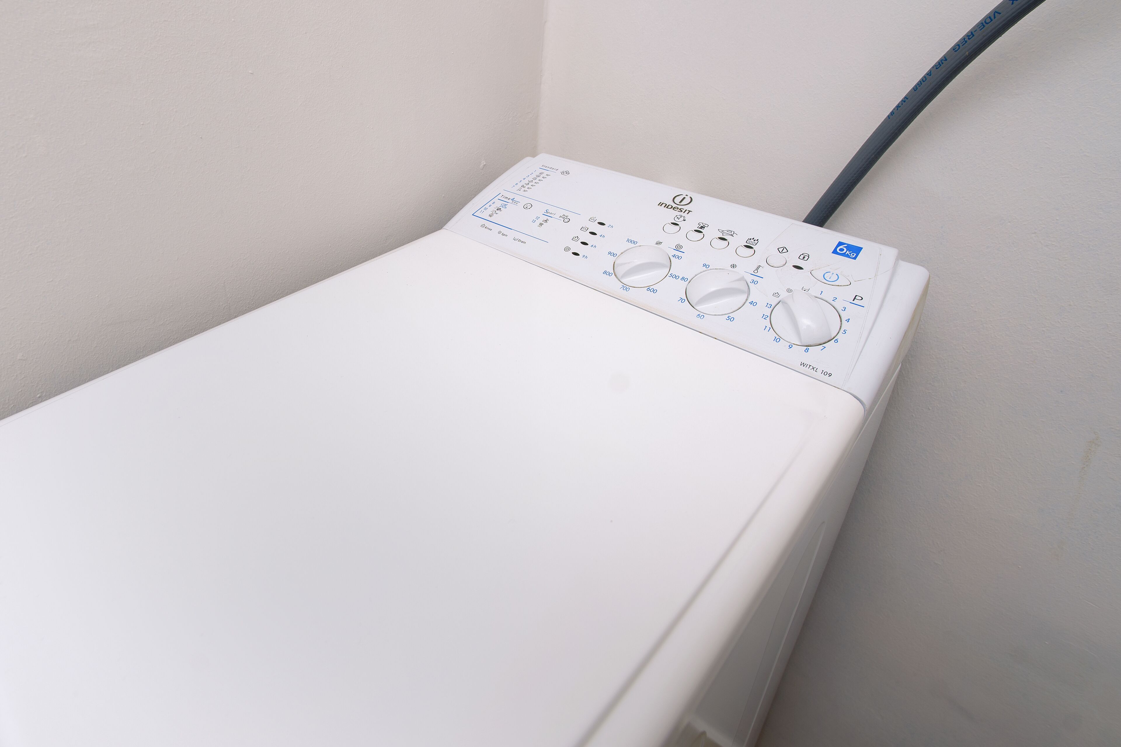 A white washing machine with control knobs and a power cord plugged in.