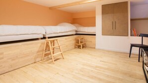 A room with two beds, wooden flooring, a wardrobe, and a small stool. - Central apartment for 4-9 people with parking in Cauterets (Cauterets)