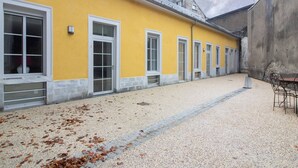 A yellow building with multiple windows and a gravel courtyard. - Central apartment for 4-9 people with parking in Cauterets (Cauterets)